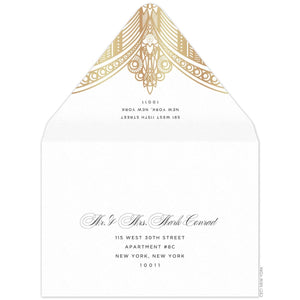 White envelope, gold deco pattern on the tip of the envelope flap. Black san serif return address. Black block and script mailing address on the front of the envelope.