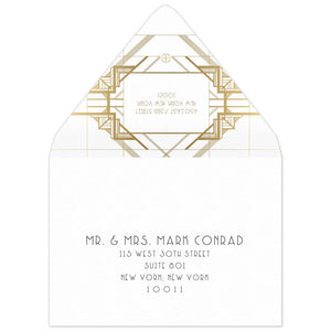 White envelope with gold geometric lines on the back flap. White box in between the lines of a deco font of the reply address. Black deco mailing address centered on the front of the envelope.