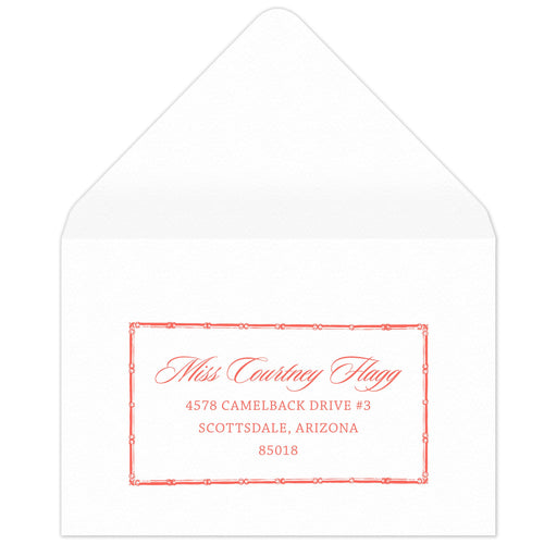 Bamboo rectangle holding block and script coral return address on a white envelope.