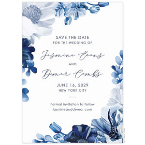 White invitation with blue watercolor flowers on the top left and bottom right corner. Center aligned navy block and script font.